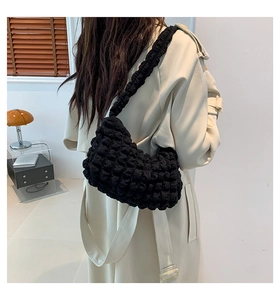 Model view of black quilted puff shoulder bag with textured fabric and cloud design
