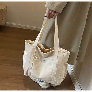 Détail du sac cabas en toile avec poches avant et bouton pression en scène décontractée