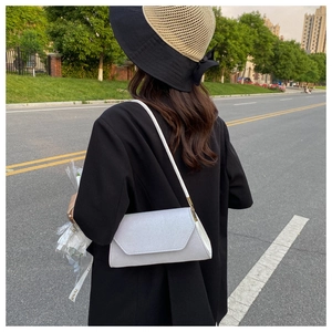 Detailansicht einer weißen Baguette-Tasche aus Leder mit minimalistischer Klappe und Riemen