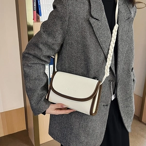 Minimalist beige crossbody bag with contrast piping and woven strap on a model
