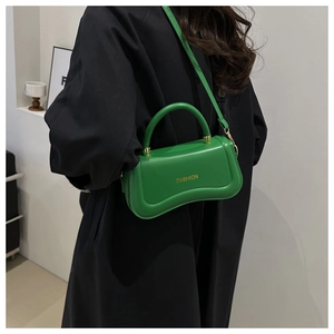 Detail of green bag with gold Fashion lettering and curved bottom on black coat