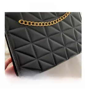 Close-up of black quilted diamond pattern leather and gold metal chain strap detail