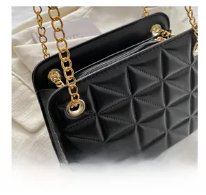 Close-up of black quilted faux leather crossbody bag with golden chain and metal grommets