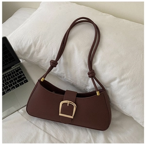 Detail of dark brown leather underarm bag with gold metal buckle and knotted strap