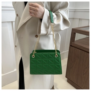 Detail of green quilted shoulder bag with geometric stitching and golden chain strap