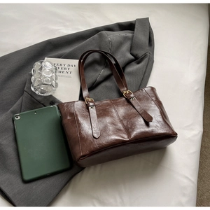 Detailed view of dark brown oil wax leather tote bag with elegant golden buckles