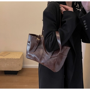 Detail of a vintage dark brown leather tote bag with metallic ring and smooth texture