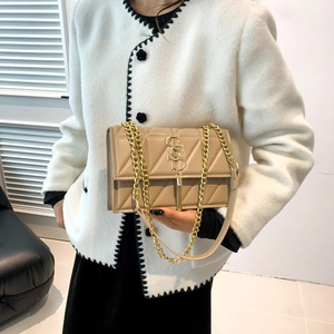 Quilted beige crossbody bag with gold S-lock and chain strap on white tweed coat