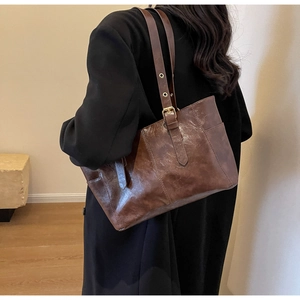 Detail of adjustable shoulder strap and gold buckle on a retro brown tote bag