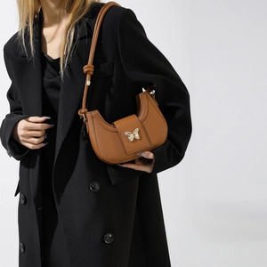 Brown pebble grain crescent shoulder bag with golden butterfly buckle and knot strap detail