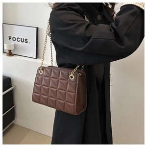 Close-up of elegant brown quilted leather crossbody bag with golden chain strap detail