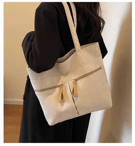 Detail view of beige corduroy tote bag showing side carry style and ribbed fabric texture