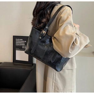 Detail showing the adjustable long straps and glossy texture of this black tote bag