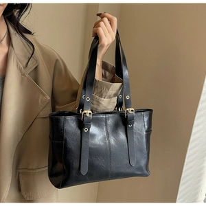 Detail view of black tote bag featuring vintage wrinkled leather texture and gold buckles
