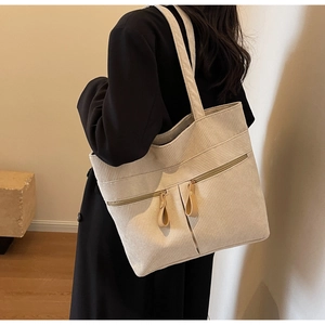 Detail of cream corduroy tote bag featuring front dual zipper pockets and vertical texture