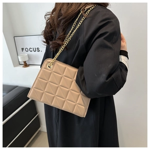 Detail of khaki leather shoulder bag featuring geometric quilted pattern and gold chain strap