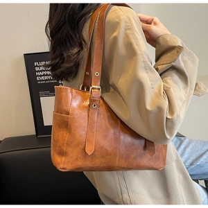 Close-up of vintage brown tote bag with gold buckle hardware and premium leather texture