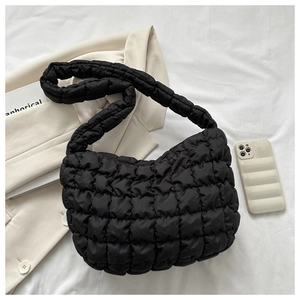 Detail of black quilted cloud bag showing puffed texture and wide shoulder strap