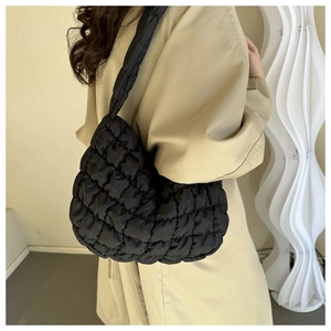 Close-up of black quilted puffer bag with cloud texture on a trench coat model