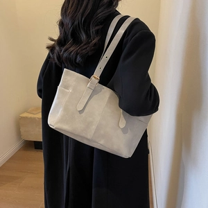 Minimalist beige leather tote bag with adjustable straps and vertical stitching detail