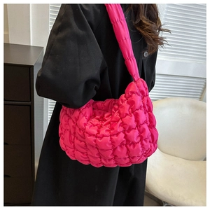 Detailed view of pink quilted cloud bag on shoulder featuring soft pleated nylon fabric