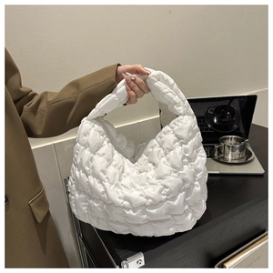 White quilted puffer handbag held by a model in a professional office setting