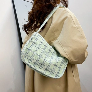 Light green checkered hobo bag worn with a beige trench coat for a minimalist look