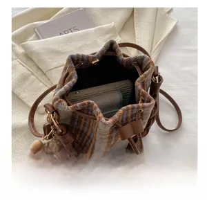 Macro view of plaid bucket bag interior showing capacity and plush bear charm detail