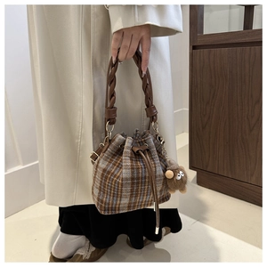 Detailed view of checkered wool bucket bag with drawstring and plush charm accessory