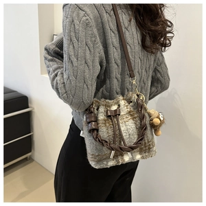 Detail view of plaid plush bucket bag with leather woven handle and cute doll charm