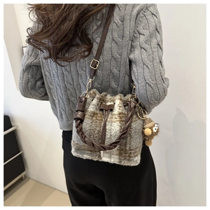 Detail of checkered plush bucket bag with cute monster charm and woven brown handle