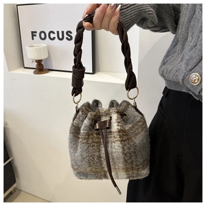 Detailed view of the plaid wool bucket bag with a braided leather handle and drawstring closure