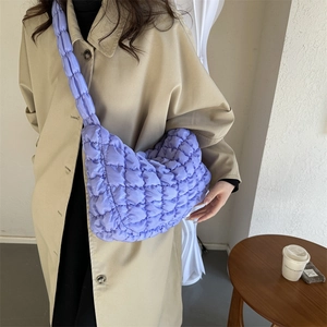 Lilac quilted cloud puffer bag with puffy texture shown on a crossbody model wearing a coat