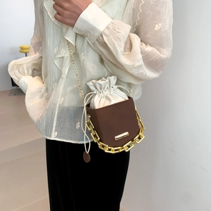 Brown leather bucket bag with white drawstring insert and stylish thick gold chain strap