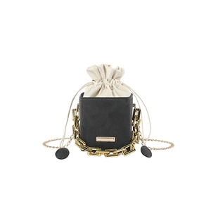 Minimalist drawstring bucket bag with black leather and white pouch featuring gold chain