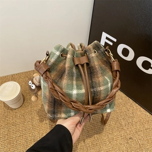 Close-up of wool plaid bucket bag with leather drawstring and plush charm accessory