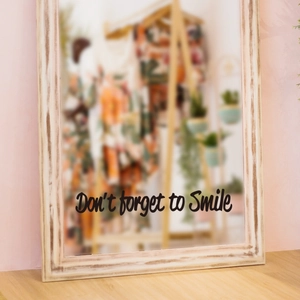 Gros plan du texte 'Don't forget to Smile' sur un cadre de miroir blanc rustique