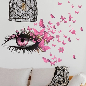 Stickers muraux œil artistique et papillons roses posés derrière un canapé de salon