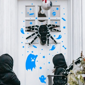Halloween door decor featuring a large spider, blue ghosts and kids in black cloaks