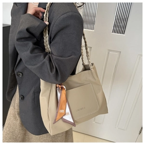 Model view of khaki pebbled leather shoulder bag with woven straps and printed scarf