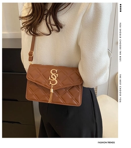 Detailansicht der braunen Stepptasche mit goldenen Beschlägen und Fransenanhänger