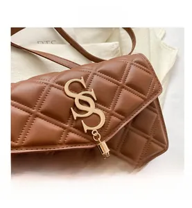 Detail der braunen gesteppten Ledertasche mit goldener SCS-Schnalle und Metallquaste
