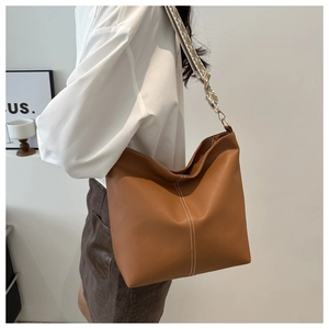 Detail of brown pebbled leather bucket bag with colorful ethnic style woven wide strap