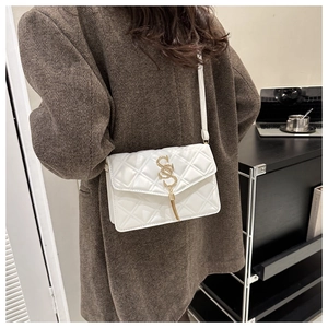 Detailansicht der weißen Stepptasche mit goldenem S-Logo und dekorativer Quaste