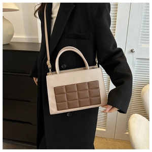 Detail of vintage two-tone crossbody bag with square embossed pattern and beige strap