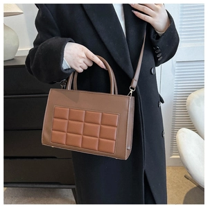 Brown patchwork crossbody bag with quilted panel worn by a model in a black coat