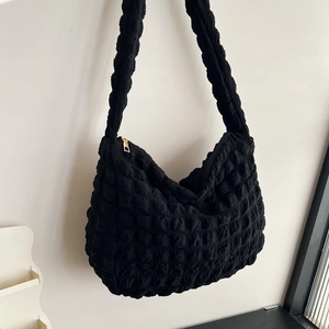 Detail of the black popcorn fabric texture and metal zipper closure on shoulder bag