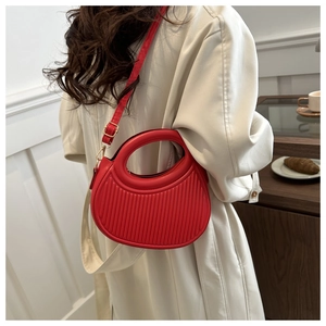 Détail du sac croissant rouge avec texture plissée et poignée ronde chic