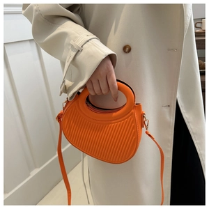 Détail d'un sac demi-lune orange vif avec texture côtelée et boucles dorées