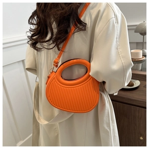 Détail du sac demi-lune orange vif avec texture côtelée et poignée ronde évidée